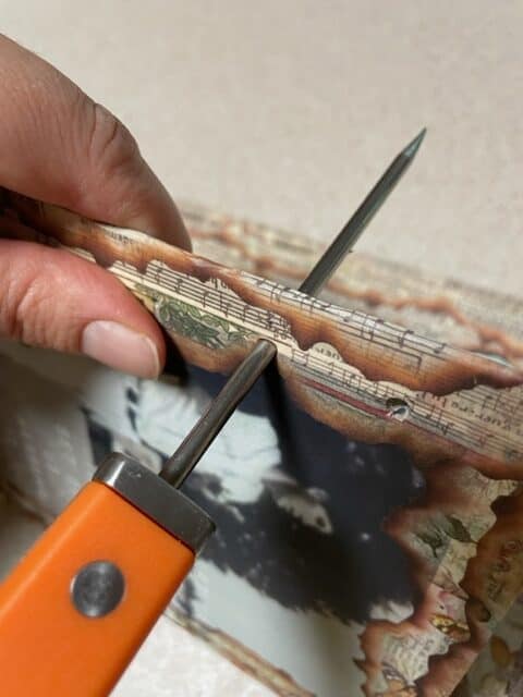 Puncturing the cover with an awl to prepare for Coptic binding a watercolor journal.